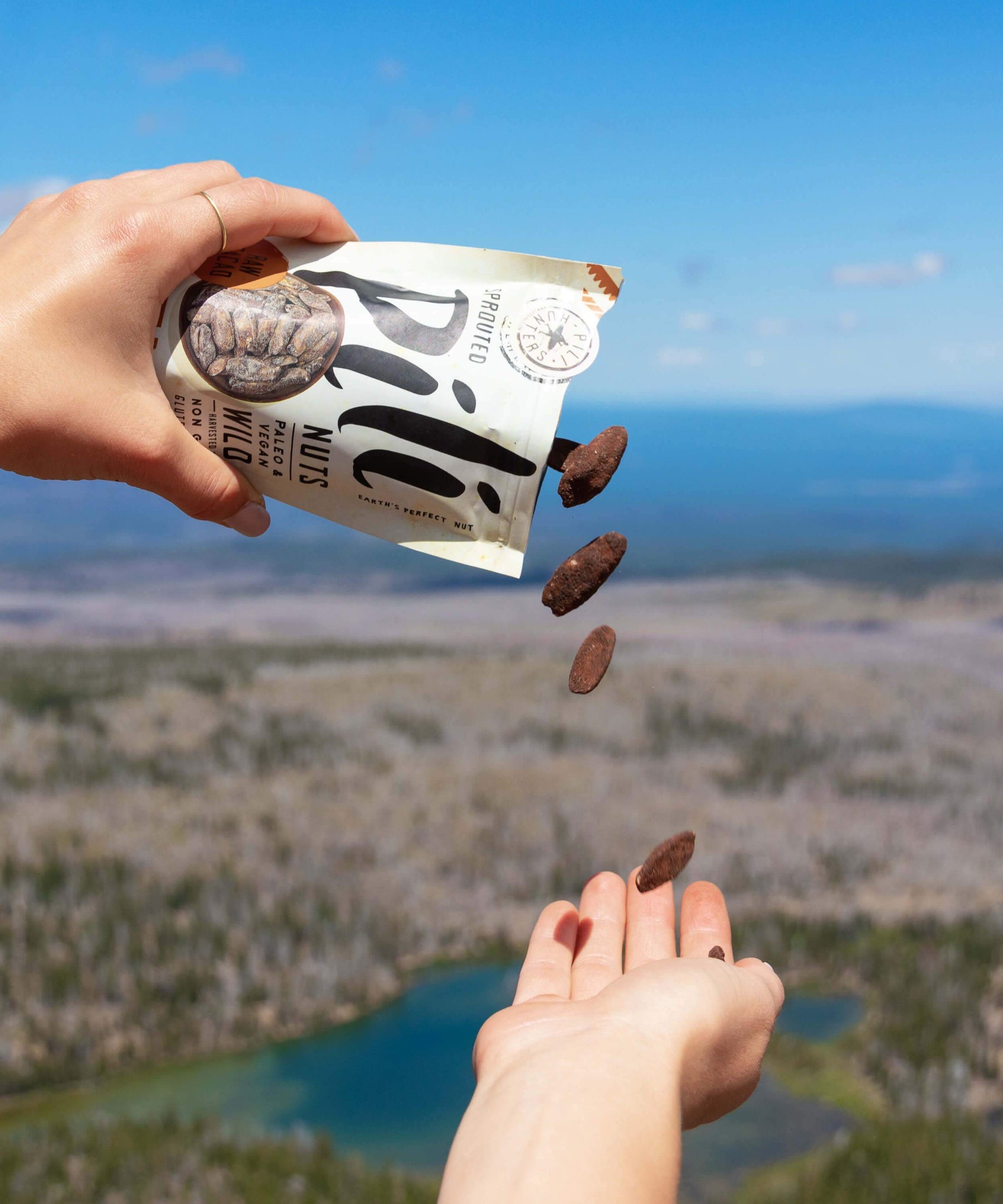 Cacao Pili Nuts falling out of packaging in front of a mountain landscape